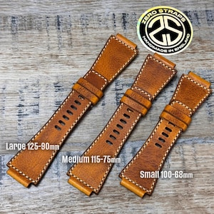 May include: Three brown leather watch straps in different sizes: Large (125-90mm), Medium (115-75mm), and Small (100-68mm). Each strap has white stitching and adjustment holes. The straps are displayed on a wooden surface.