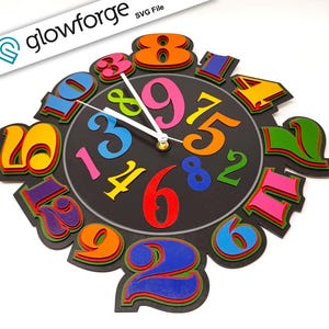Puede incluir: Un reloj de pared colorido y en capas con una esfera negra y números dimensionales multicolores. Las manecillas del reloj son blancas y los números son de varios colores brillantes. El reloj tiene un diseño moderno y lúdico.