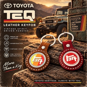 Puede incluir: Dos llaveros redondos de cuero con anillas metálicas, uno en color tostado y otro en rojo, cada uno con un emblema circular blanco con el logotipo Toyota TEQ. El llavero tostado tiene un fondo degradado amarillo y naranja, el rojo es liso.