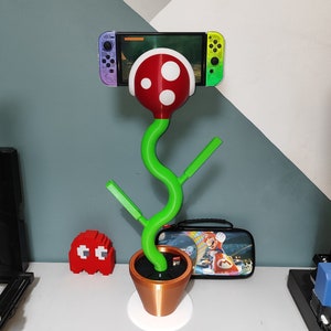 Bring some fun and whimsy to your gaming setup with this unique Nintendo Switch Piranha Stand! Designed to look like a piranha plant from the beloved Super Mario series, this stand securely holds your Switch while charging it via the USB-C port.