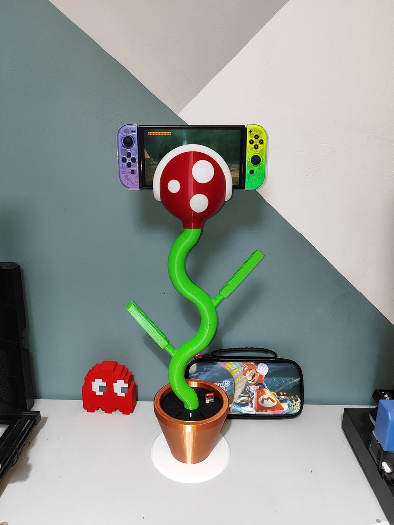 Bring some fun and whimsy to your gaming setup with this unique Nintendo Switch Piranha Stand! Designed to look like a piranha plant from the beloved Super Mario series, this stand securely holds your Switch while charging it via the USB-C port.