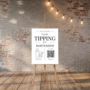 May include: A white rectangular sign on a wooden easel featuring black text that reads Love Your Drink? Consider Tipping Your Bartender. The sign includes a line drawing of a cocktail shaker and a glass, a QR code labelled Tip Here, and the text Great Drinks Better With You and Thank You.