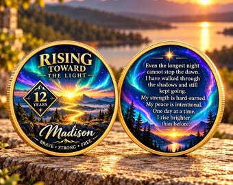 May include: Two gold-rimmed circular medallions featuring a vibrant sunrise over mountains and forests. The left coin displays the text RISING TOWARD THE LIGHT, 12 YEARS, Madison, BRAVE, STRONG, FREE. The right coin features an inspirational quote.