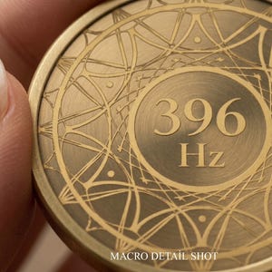 May include: Close-up of a bronze-colored coin with intricate geometric patterns. The coin features the number "396" and "Hz" in a central circle. The text "MACRO DETAIL SHOT" is visible at the bottom.