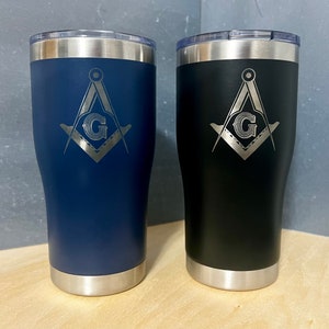 May include: Two stainless steel tumblers with a black and blue finish. Both tumblers feature a laser engraved Masonic symbol with a 'G' in the center.