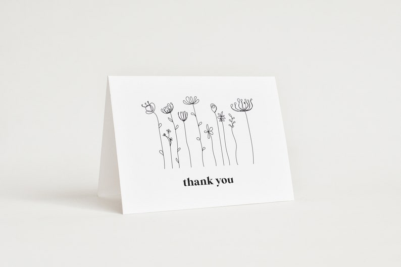 A minimalist wildflower 5x3.5 Landscape Baby Shower Thank You Card, consiting of bloack monoline flowers, and the text is in black. You can personalise your editable Thank You Card template in Corjl.