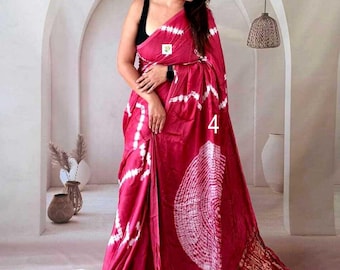May include: A magenta saree featuring a white tie-dye circular pattern and a wide metallic gold border at the hem. The garment is draped over a black sleeveless blouse. The number 4 is printed in white on the fabric of the saree.