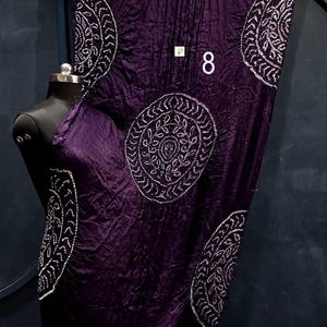 May include: A deep purple fabric wrap featuring white circular mandala-style patterns and a metallic gold border at the top and bottom edges. The fabric has a crinkled texture and displays the number 8 in white text on the front surface.