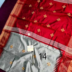 May include: A red and grey sari with a decorative pattern. The red section has small, square yellow and red designs. The grey section has the number 14 printed on it. The sari has a gold border.