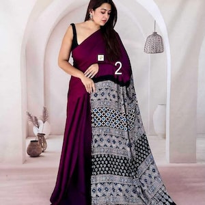 Puede incluir: Un sari de color morado intenso con un cuerpo de color s&oacute;lido y un pallu negro en contraste adornado con intrincados patrones geom&eacute;tricos en blanco, azul y negro. La prenda incluye el n&uacute;mero 2 impreso y una peque&ntilde;a etiqueta cuadrada.