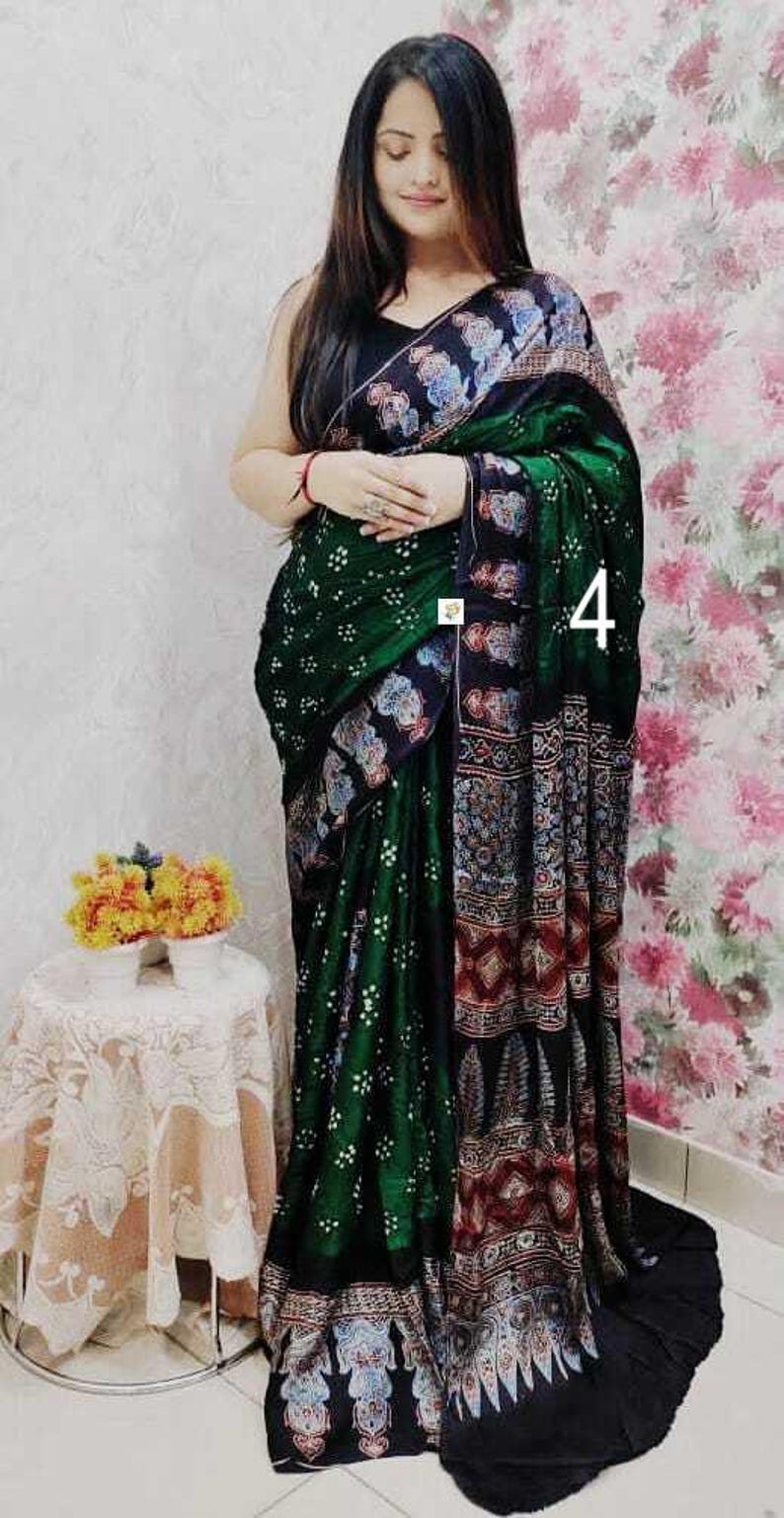 May include: A dark green and black saree featuring a white dotted bandhani pattern on the main body, complemented by a wide border with intricate multi-colored floral and geometric motifs. The number 4 is visible on the fabric.