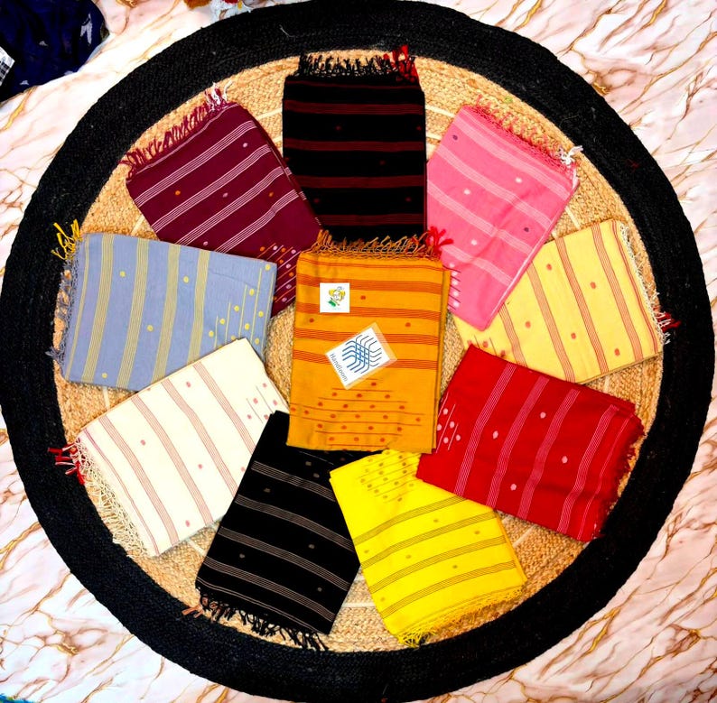 May include: A collection of ten rectangular cotton scarves arranged in a circular pattern. Each scarf features a distinct solid color including maroon, black, pink, light blue, mustard yellow, cream, red, and bright yellow, with thin stripes and small dots.