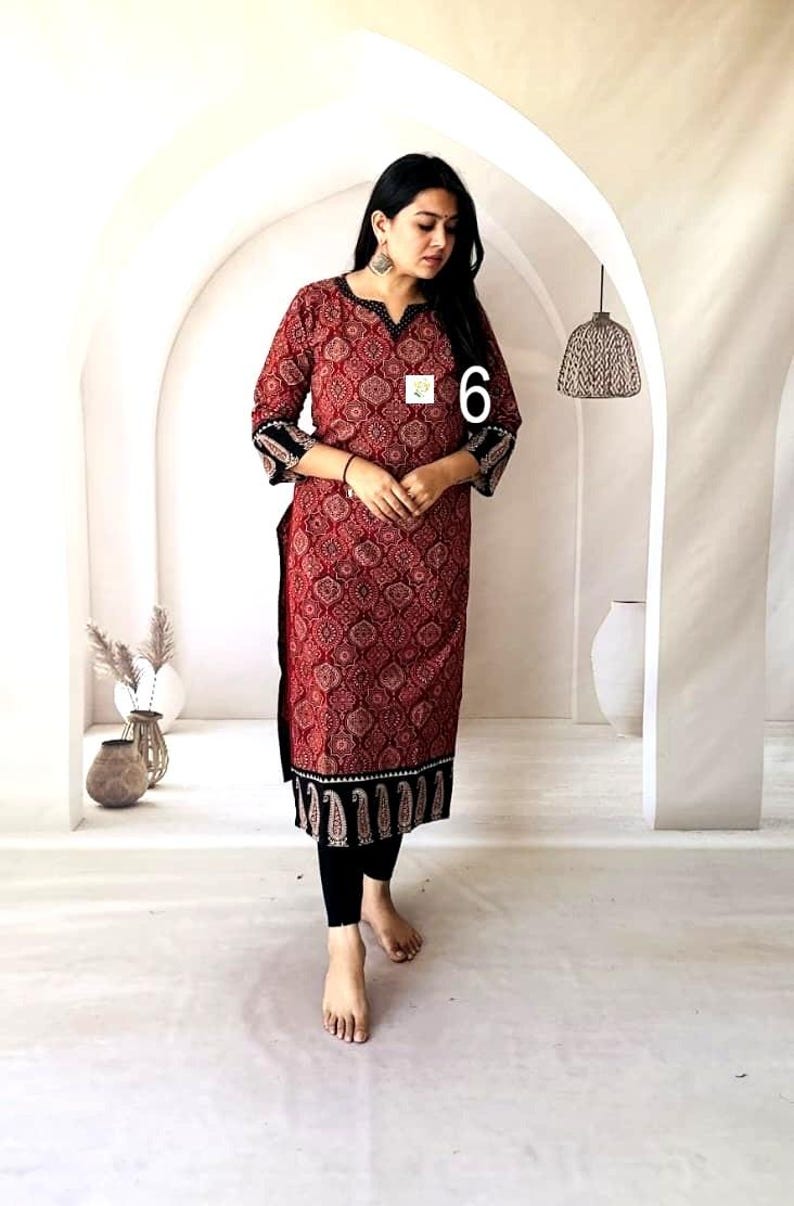 Puede incluir: Una t&uacute;nica larga roja con un estampado de cachemira, ribetes negros y mangas tres cuartos. La t&uacute;nica se combina con leggings negros. El n&uacute;mero "6" es visible en la t&uacute;nica. El atuendo es adecuado para ropa casual.