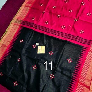 May include: A striking red and black textile with a geometric design. The fabric displays a vivid red field adorned with small white and red square patterns. A black section at the bottom has the number "11" printed on it. The edges are trimmed with gold and black stripes.