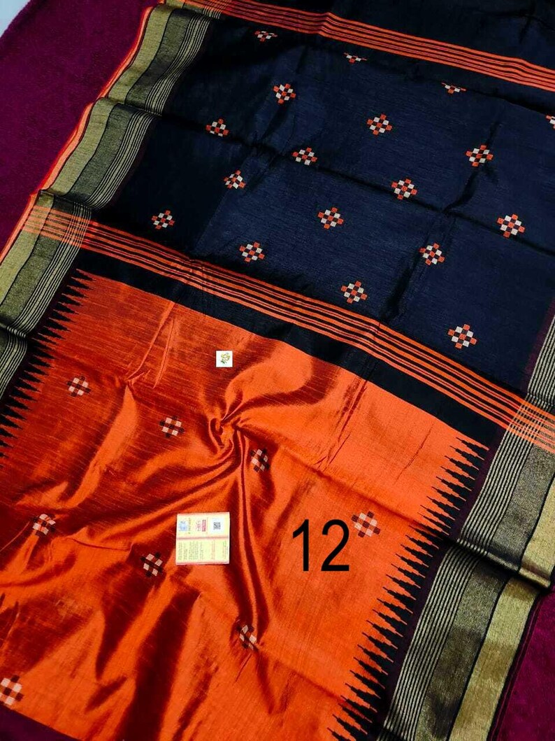 May include: A dark blue and orange saree with a detailed design. The saree features a dark blue upper portion with small, repeating floral patterns in white and orange. The lower portion is orange with a repeating pattern and the number "12".