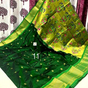 Op de afbeelding: Een donkergroene sari met een brede, fel limoengroene rand met ingewikkelde pauw- en bloemmotieven in roze, blauw en groen. Het hoofdgedeelte van de stof is diep bosgroen met kleine goudkleurige stervormige patronen over het gehele oppervlak.