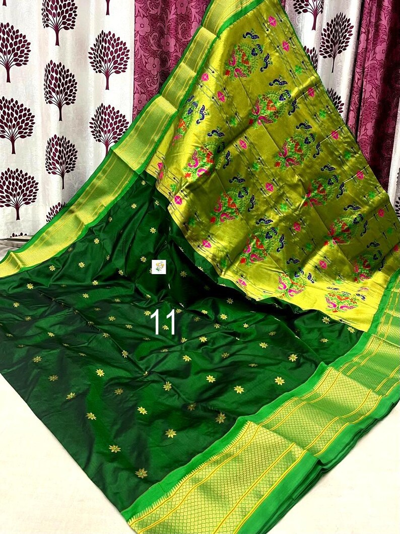 Op de afbeelding: Een donkergroene sari met een brede, fel limoengroene rand met ingewikkelde pauw- en bloemmotieven in roze, blauw en groen. Het hoofdgedeelte van de stof is diep bosgroen met kleine goudkleurige stervormige patronen over het gehele oppervlak.