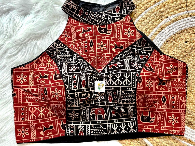 May include: A red and black halter top with a geometric pattern. The top is made of cotton and has a high neckline. The pattern is made up of small squares and triangles.