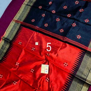 May include: A colourful textile with a striking contrast of colours and patterns. The upper section is a deep navy blue, decorated with small, repeating red and white floral motifs. The lower section is a bright red, with a black zigzag border. The number "5" is visible.
