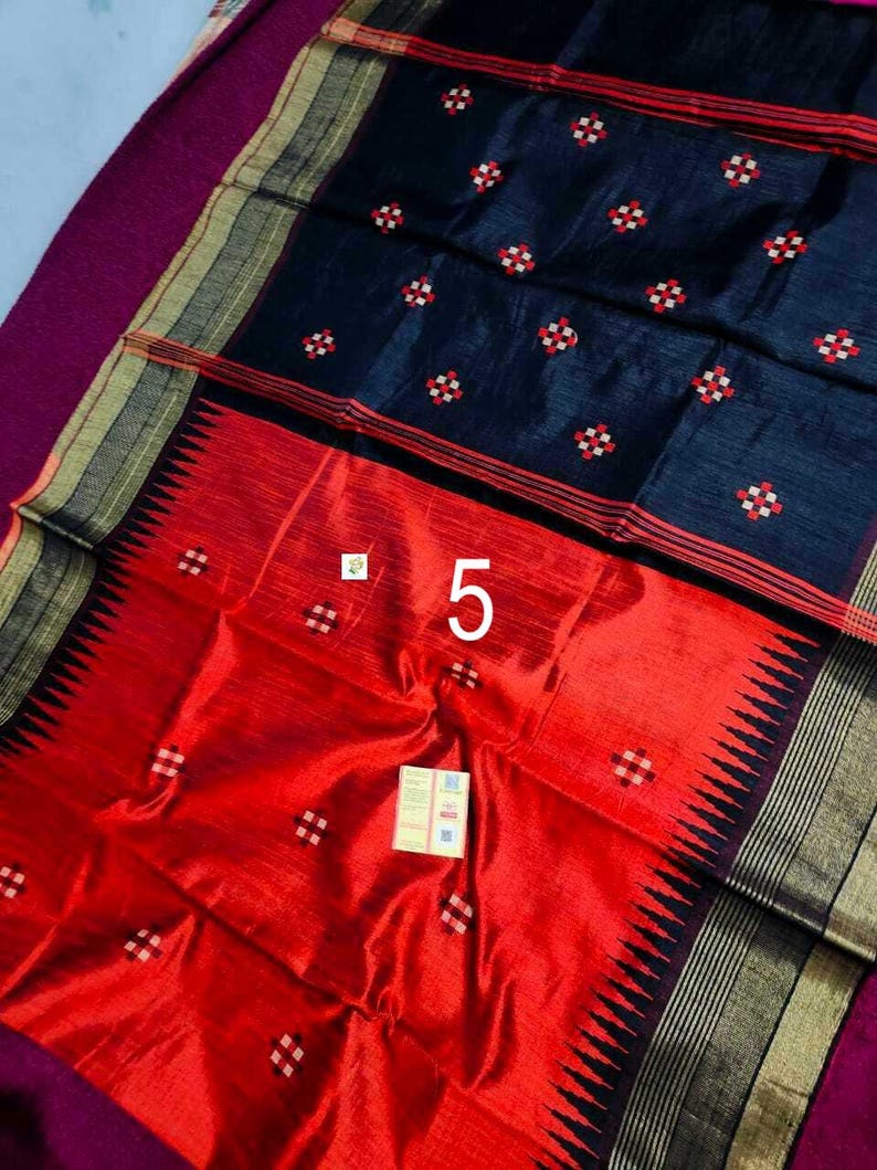 May include: A colourful textile with a striking contrast of colours and patterns. The upper section is a deep navy blue, decorated with small, repeating red and white floral motifs. The lower section is a bright red, with a black zigzag border. The number "5" is visible.