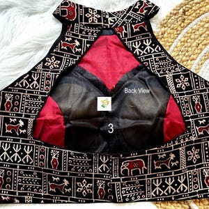 Puede incluir: Blusa de cuello alto con estampado en blanco y negro, forro rojo y superposici&oacute;n de tela negra transparente. La parte posterior de la blusa tiene el texto "Back View" escrito en ella.