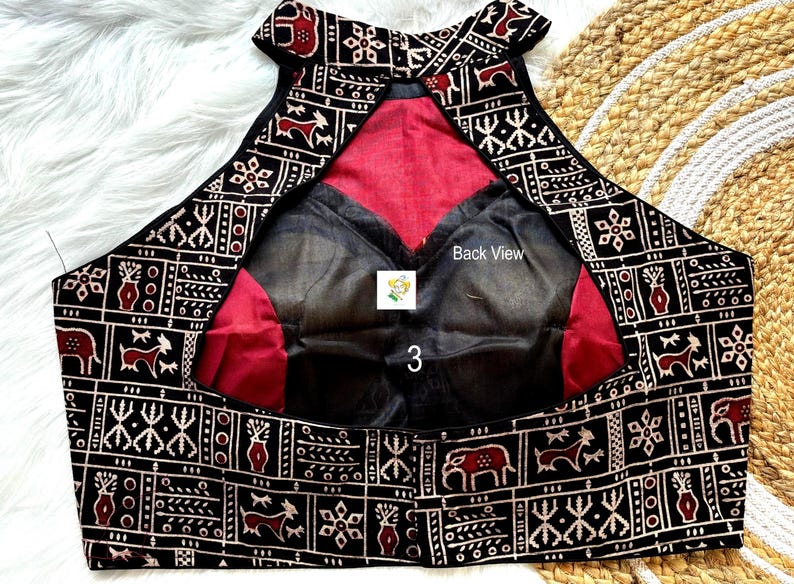 Puede incluir: Blusa de cuello alto con estampado en blanco y negro, forro rojo y superposici&oacute;n de tela negra transparente. La parte posterior de la blusa tiene el texto "Back View" escrito en ella.