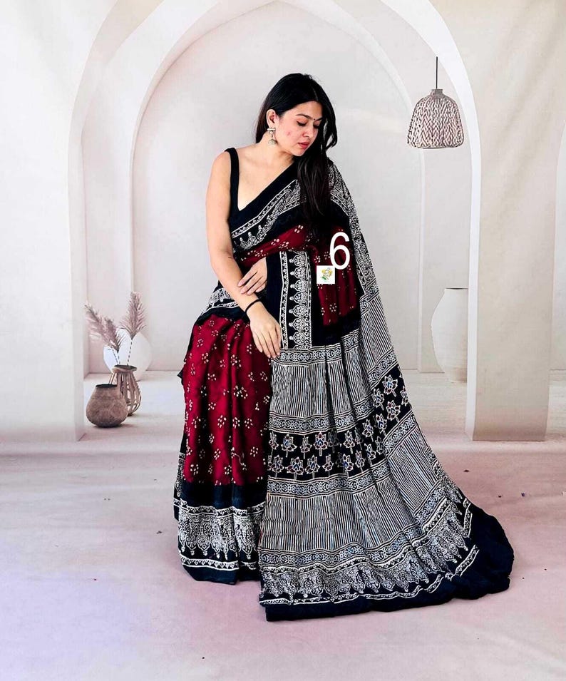 May include: A saree featuring a deep maroon section with small white floral patterns and a contrasting black section with intricate white geometric and botanical block print designs, including a wide border with detailed white motifs.
