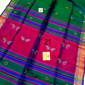 Puede incluir: Un sari verde y magenta con un patr&oacute;n repetido de mariposas, rayas horizontales en azul y morado, y peque&ntilde;os motivos de diamantes dorados. La tela muestra el n&uacute;mero 21 y una peque&ntilde;a etiqueta rectangular con texto en el centro de la pieza.