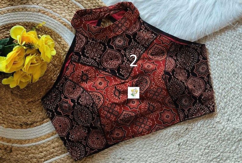 Puede incluir: Un top halter de patr&oacute;n rojo y negro con una abertura de ojo de cerradura en la espalda. El top tiene un dise&ntilde;o geom&eacute;trico con el n&uacute;mero "2" impreso en la parte delantera.