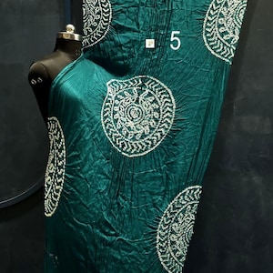 May include: A dark teal fabric drape featuring white circular patterns with intricate detailing and a crinkled texture. The fabric has a metallic gold border at the bottom and includes the number 5 printed in white near the centre of the material.