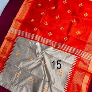 May include: A striking red and grey textile with a repeating pattern of small, colourful squares. The fabric has a textured appearance and features a border with a striped design. The number "15" is printed on the grey section.