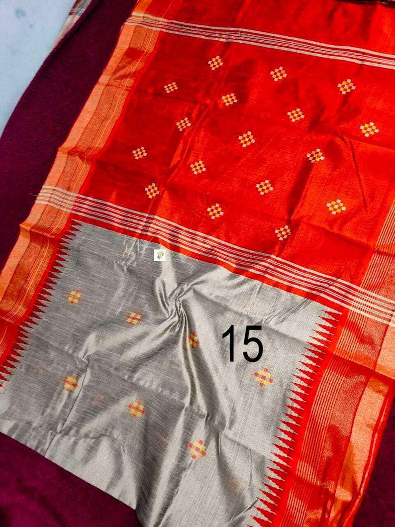May include: A striking red and grey textile with a repeating pattern of small, colourful squares. The fabric has a textured appearance and features a border with a striped design. The number "15" is printed on the grey section.