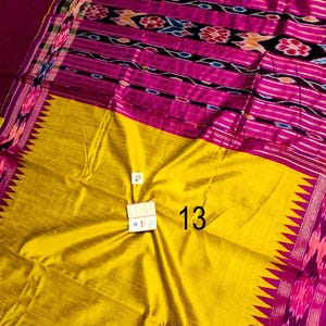 May include: A vibrant textile with a yellow and fuchsia color scheme. The fabric features intricate patterns in shades of pink, black, and orange. The number "13" is visible on the yellow portion of the textile. The edges are adorned with a decorative border.