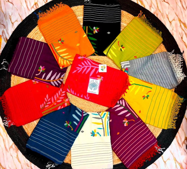 May include: A collection of ten rectangular fabric scarves arranged in a circular pattern. Each scarf features horizontal stripes, a floral motif, and fringed edges. The colors include orange, black, lime green, gray, red, yellow, dark blue, white, and purple.