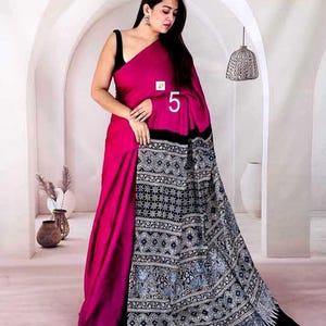 Puede incluir: Un sari magenta que presenta un drapeado de color s&oacute;lido y un pallu negro en contraste adornado con intrincados patrones geom&eacute;tricos blancos y azules. La prenda incluye una blusa negra sin mangas y muestra el n&uacute;mero 5 en la tela.