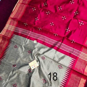May include: A colourful textile in fuchsia and grey. The fuchsia section has a pattern of small white squares, while the grey section features a floral design. The border is red with white stripes. The number "18" is visible.
