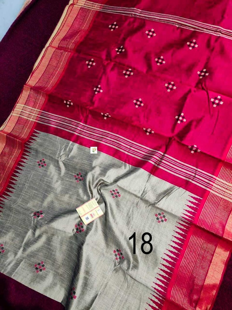 May include: A colourful textile in fuchsia and grey. The fuchsia section has a pattern of small white squares, while the grey section features a floral design. The border is red with white stripes. The number "18" is visible.