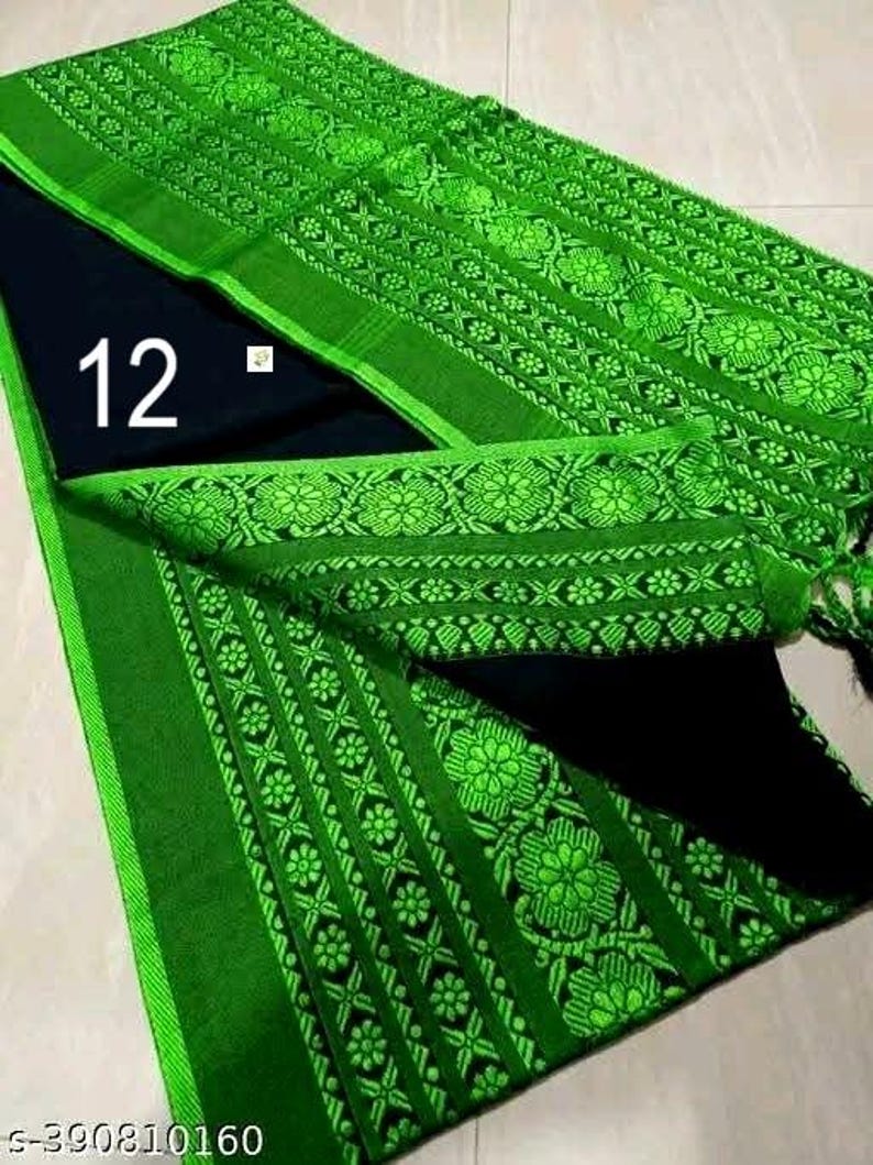 K&ouml;nnte beinhalten: Gr&uuml;ner Stoff mit aufwendigen Blumenmustern und einem kontrastierenden schwarzen Abschnitt. Der Stoff hat einen leuchtend gr&uuml;nen Rand und dekorative Elemente. Die Zahl "12" ist in Wei&szlig; sichtbar. Das Design deutet auf ein traditionelles Kleidungsst&uuml;ck oder einen Stoff hin.