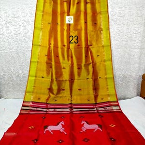 Puede incluir: Un sari de colores amarillo y rojo vibrantes que presenta una secci&oacute;n superior de color amarillo dorado con peque&ntilde;os motivos de diamantes oscuros y una secci&oacute;n inferior de color rojo brillante con dos figuras de caballos blancos y bordes.