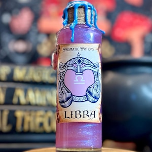May include: A glass bottle filled with a shimmering pink liquid, labeled "Libra" with a scale symbol. The bottle has a blue wax seal and is displayed on a wooden stand. The words "Prismatic Potions" are also visible.