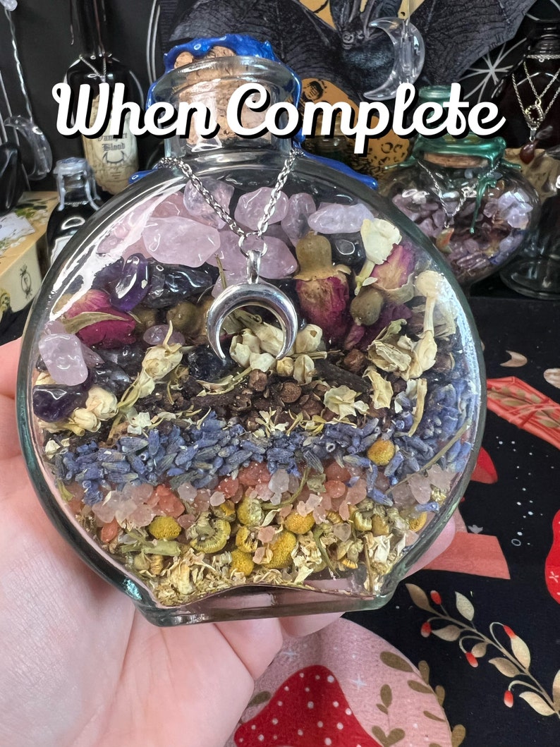 May include: A glass jar filled with dried flowers, herbs, crystals, and a silver crescent moon charm. The jar is labeled "When Complete".