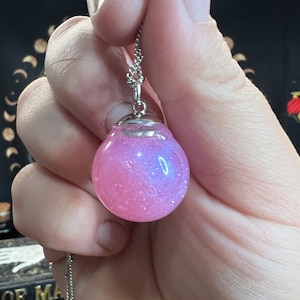 May include: A silver chain necklace with a pink iridescent glass orb pendant.
