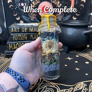 May include: A glass bottle filled with various dried herbs, flowers, and crystals. The bottle is sealed with a cork and has a yellow wax seal. The bottle is labeled "When Complete".