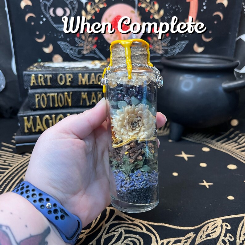 May include: A glass bottle filled with various dried herbs, flowers, and crystals. The bottle is sealed with a cork and has a yellow wax seal. The bottle is labeled "When Complete".