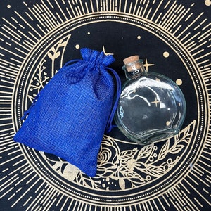 May include: A blue burlap pouch and a clear glass bottle with a cork stopper, both sitting on a black background with a gold sunburst design.