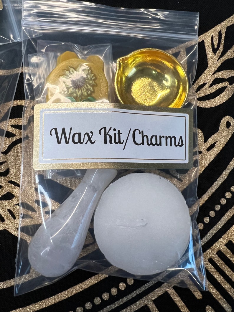 May include: A clear plastic bag containing a wax kit and charms. The kit includes a small white round wax block, a white spoon-shaped tool, a gold-colored metal dish, and a yellow paper charm with a sunflower design. The bag has a label that reads "Wax Kit/Charms".