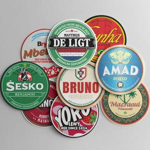 Puede incluir: Un conjunto de posavasos redondos con varios diseños y texto. Los posavasos presentan nombres como "De Ligt", "Bruno Fernandes" y "Amad Diallo", junto con frases como "Premium Goalscorer" y "Red Since 2024". Los posavasos tienen un aspecto vintage.