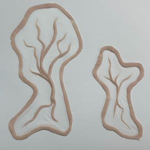 Puede incluir: Dos formas abstractas y orgánicas con un contorno marrón claro y patrones ramificados en el interior. Las formas se colocan sobre un fondo blanco liso, creando una composición minimalista y artística.