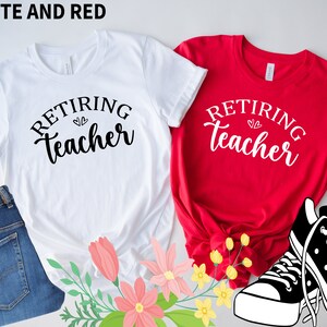 以下が含まれることがあります： 「Retiring Teacher」の文字が入った白と赤のTシャツ。白いシャツはブルージーンズとピンクの花と組み合わされています。黒と白のスニーカーが赤いシャツの隣にあります。「WHITE AND RED」の文字が上部にあります。