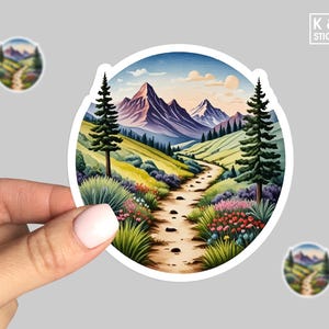 May include: A round sticker with a colorful illustration of a winding path through a mountain valley. The path is lined with wildflowers and trees. The mountains are purple and blue, and the sky is a light blue with a few clouds.